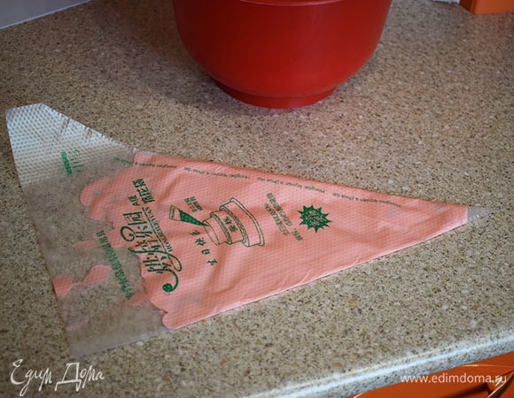 Переложить розовый крем в кондитерский мешок. Распределить его по мешку, как на фото. Затем раскрыть мешок и в середину выложить белый крем. Затем взять другой кондитерский мешок с насадкой «закрытая звезда». Отрезать у мешка с кремом кончик и вложить его в мешок с насадкой.