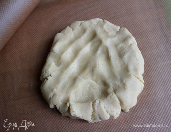 Достать тесто из холодильника, отделить часть теста для бортиков. Остальное тесто положить на рабочую поверхность, покрытую бумагой для выпечки. Немного расплющить руками.