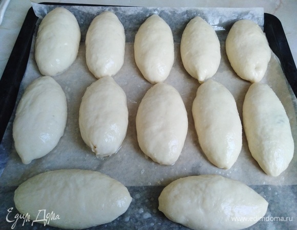 Разогреть заранее духовку. Пирожки выложить на противень, застеленный пергаментной бумагой и смазанный растительным маслом. Смазать смесью яйца с молоком или водой.