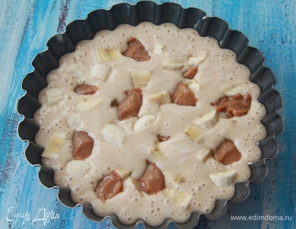 Форму смазать маслом. Вылить тесто. Банан нарезать кусочками, добавить в тесто. Густую вареную сгущенку зачерпывать чайной ложкой и также выкладывать в тесто. Лучше эти ингредиенты выкладывать не поверх теста, а в следующей очередности: тесто, бананы, карамель.