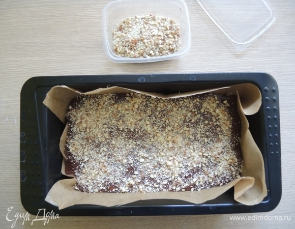 Форму застелить пергаментом. Вылить в нее тесто и посыпать сверху молотыми орехами. Поставить в духовку, разогретую до 180°C, на 30 минут.
