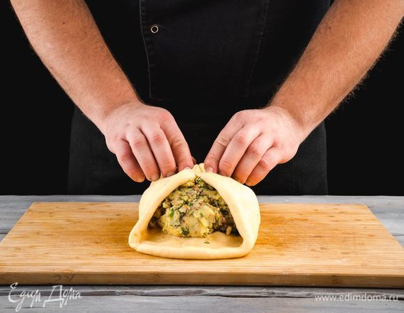 Тесто разомните в пласт толщиной 0,5 см. В середину выложите всю начинку. Концы пласта соедините сверху и разомните тесто, что бы пирог стал плоским и круглым.