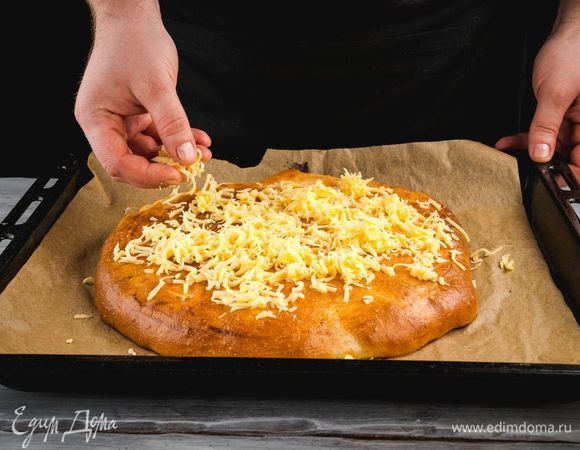 Достаньте пирог, посыпьте его обильно тертым сыром и уберите в духовку еще на 5 минут.