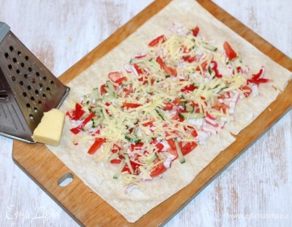 Натереть сыр и посыпать им лаваш.