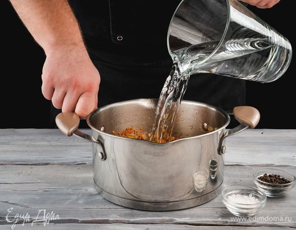 Добавьте воду, соль и перец по вкусу. Варите суп до полной готовности чечевицы 20–30 минут.