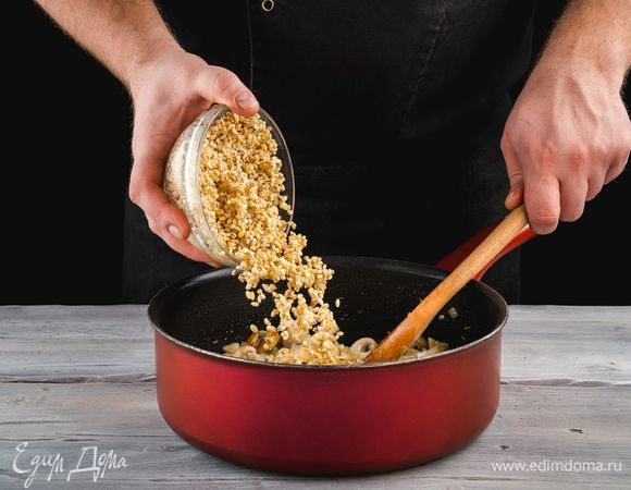 Добавьте к обжаренным грибам перловку, потушите вместе 5 минут.