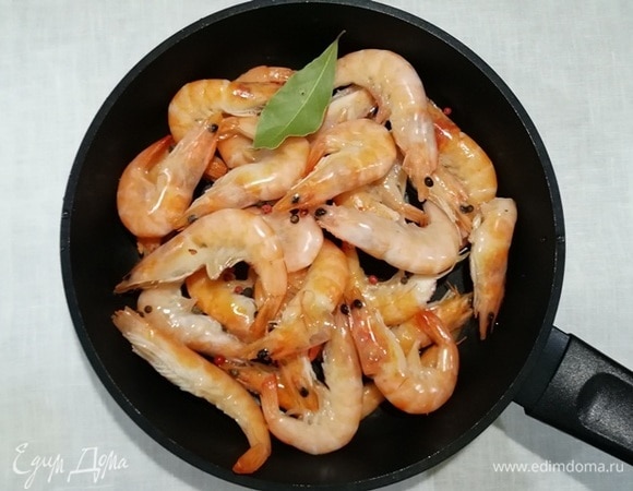 Пока запекается рыба, выкладываем замороженные креветки в сотейник, добавляем соль, перец горошком и лавровый лист.