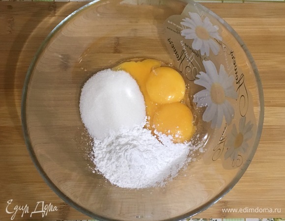 В отдельной миске смешайте желтки, сахар и крахмал. Влейте горячее молоко в желтки, интенсивно мешая венчиком.