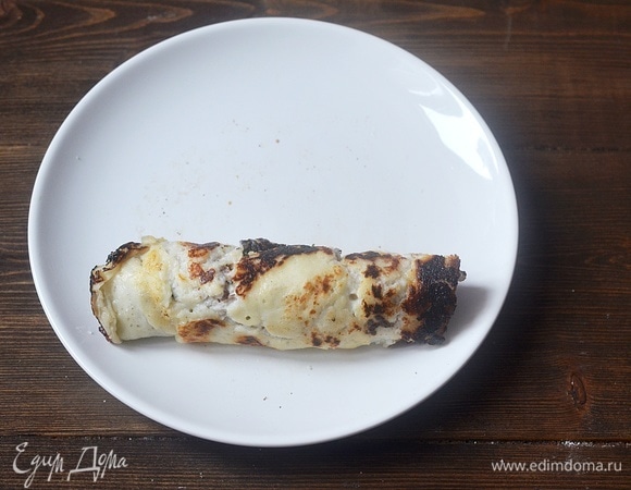 На край блина выложите начинку и сверните плотным рулетом.