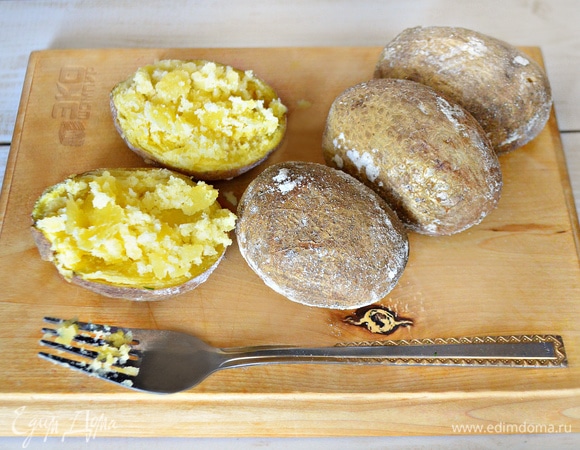 С уже готового картофеля стряхните соль, аккуратно разрежьте картофель пополам, вилкой слегка разомните сердцевину.