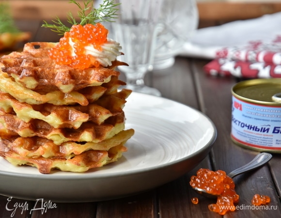 Перед подачей выложить картофельные вафли башенкой и украсить сырным кремом. Сверху щедро сдобрить красной икрой ТМ «Восточный берег» и веточкой зелени.