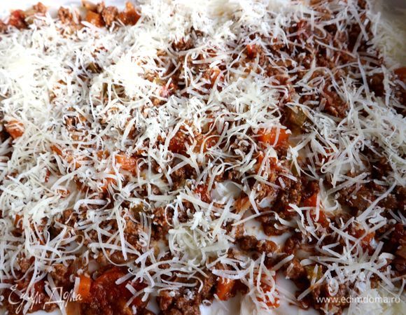 Затем равномерно поместить часть фарша и натертого сыра.