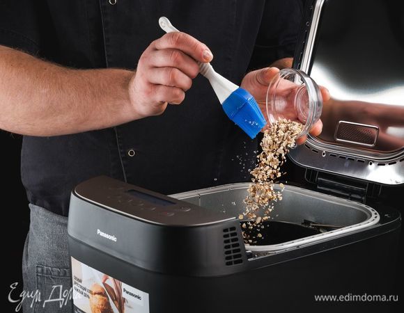 За 55 минут до окончания программы сбрызните поверхность хлеба водой и посыпьте смесью из овсяных хлопьев, семян подсолнечника, кунжута и льна.