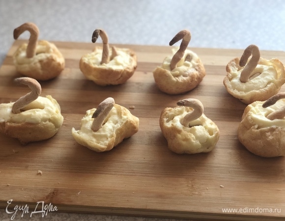 В крем воткнуть шеи (трубочки запеченные) лебедя.