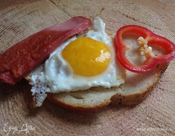 На разогретой сковородке поджарить на оливковом масле ломтики докторской колбасы, затем поджарить яйца, посолить. Можно добавить сладкий перец по желанию.