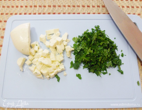 Большой шарик моцареллы нарезать кусочками, зелень петрушки измельчить.
