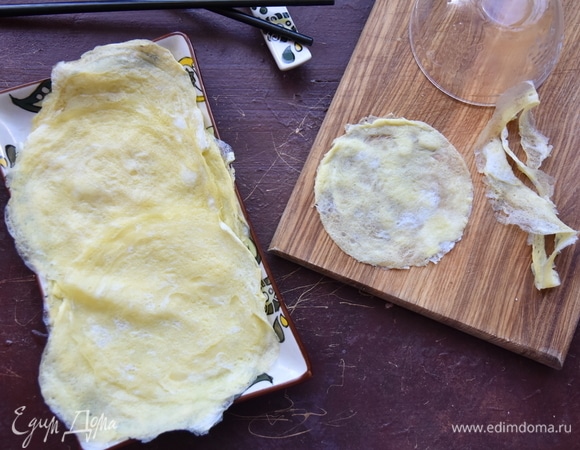 Из яичной заготовки вырезать круг диаметром меньше, чем получившиеся четвертинки листа нори.