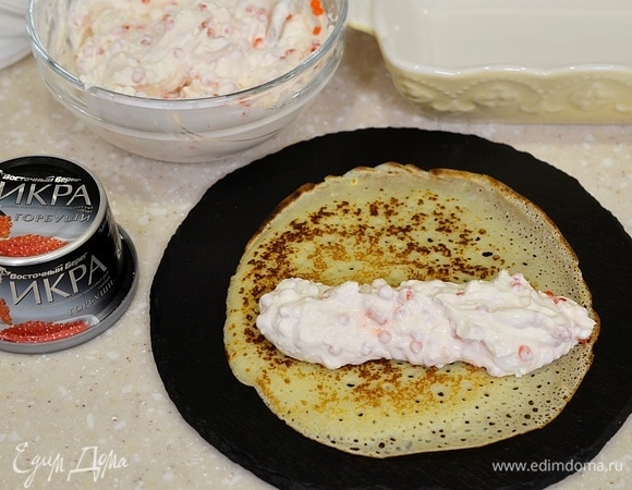 Вдоль каждого блина положите часть крема, сверните в трубочку.