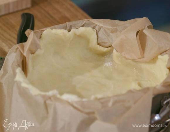 Разделить тесто на две неравные части, большую раскатать на бумаге для выпечки и поместить в разъемную форму, так чтобы получились высокие бортики, затем отправить в морозильник.