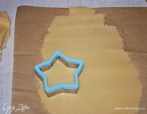 Раскатайте тесто на бумаге для выпечки, формочкой вырежьте фигурки.