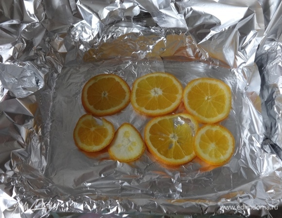 Фольгу кладем в форму в 3 слоя. Выложить половину кружков апельсинов.