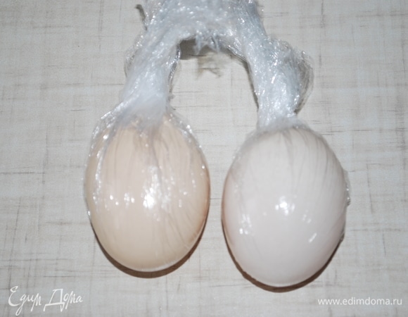 Тщательно вымойте два куриных яйца, оберните их пищевой пленкой.