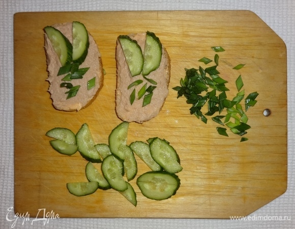 На тосты выложить кусочки огурцов и зеленый лук.