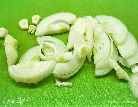 Духовку разогреваем до 180°C. Лук очищаем и нарезаем полукольцами, чеснок нарезаем поперек.