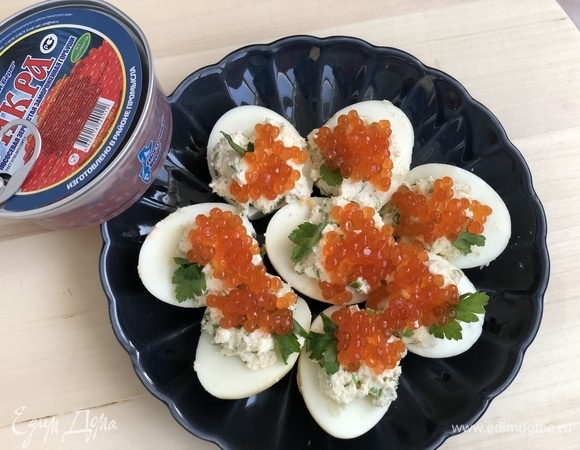 Сверху на яйца выложить красную икру ТМ «Восточный берег» и украсить веточкой петрушки.