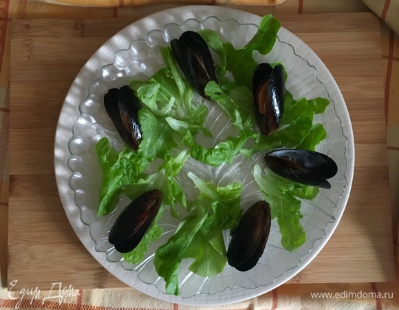 В салатницу выложить салатные листья и по краю тарелки выложить остывшие мидии.