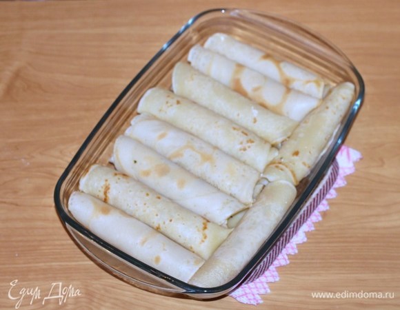 Поместить блинные рулетики в смазанную сливочным маслом форму, сверху добавить кусочки оставшегося масла, накрыть фольгой и держать в разогретой до 180°C духовке 15 минут.