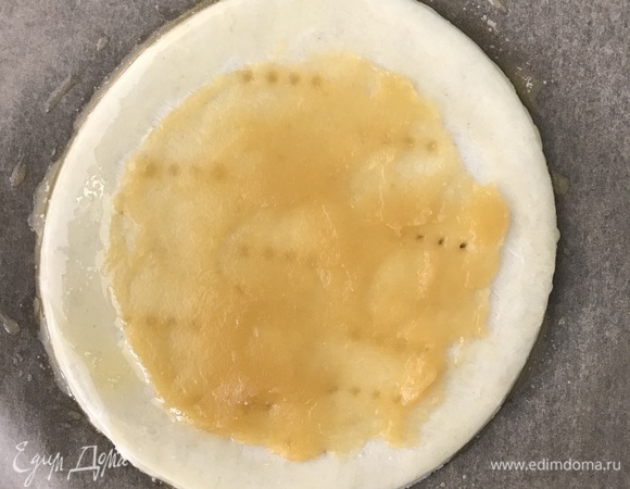 Из теста вырезать круг диаметром 16 см, наколоть вилкой, смазать 1 ст. л. яблочного пюре, оставляя 1,5 см от краев.