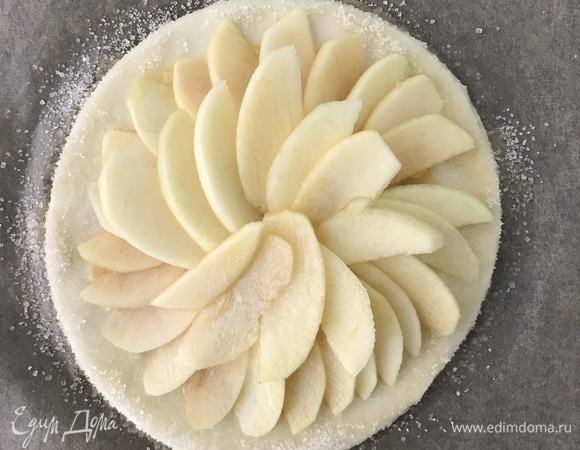 Свободную часть теста смазать 10 г растопленного сливочного масла и посыпать 10 г тростникового сахара. На пюре выложить нарезанные слайсы яблока.
