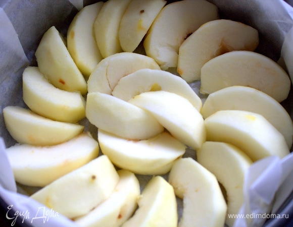 Застелить форму пергаментом, смазанным сливочным маслом, и выложить на дно дольки яблок.