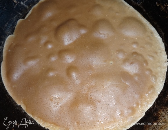 Сковороду разогреть. С помощью кисточки смазать растительным маслом. Вылить часть теста, распределив его по всей сковороде. Выпекать блинчик сначала с одной стороны до легкого румянца.