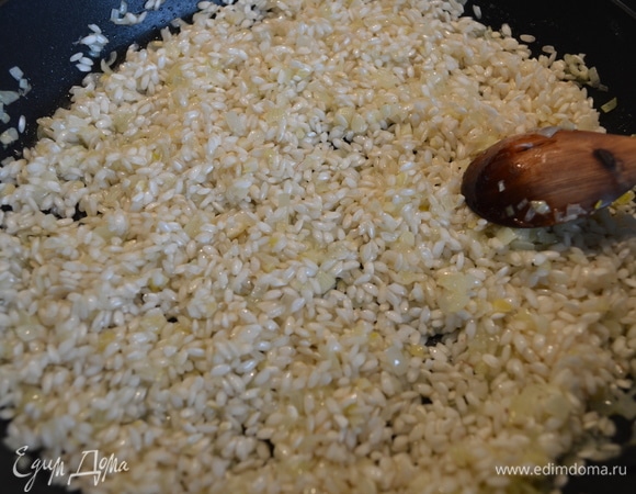 Всыпать рис и обжарить его, помешивая, пару минут.