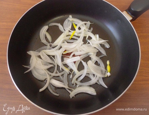 Разогреть в другой сковороде ложку растительного масла. Репчатый лук нарезать тонкими перьями, выложить лук в сковороду, добавить половину чайной ложки сахарного песка и припустить лук до прозрачности.