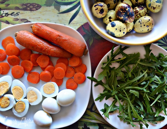 Отварите и почистите перепелиные яйца. Каждое разрежьте пополам. Морковь отварите до готовности, почистите и нарежьте кружочками. Руколу помойте и просушите.