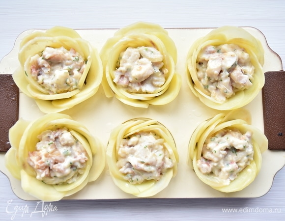 Форму для кексов смазать растительным маслом. Выложить ломтики картофеля в форме цветка. Уложить подходящий ломтик на дно каждой формочки. В центр каждого картофельного цветка уложить по 2–3 ст. л. рыбной начинки. Лепесточки слегка смазать растительным маслом. Запекать в духовке, разогретой до 180°C, до готовности картофеля. В конце выложить на начинку немного натертого сыра и включить режим «гриль», чтобы зарумянить картофельные лепесточки. Если картофель начнет сильно зарумяниваться раньше времени, накройте его фольгой.