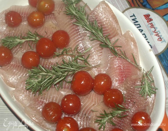 Помидоры черри смешать с оставшимся растительным маслом, орегано, черным молотым перцем и солью по вкусу. Выкладываем на рыбу. Раскладываем веточки свежего розмарина. Можно уже отправить в разогретую до 180°C духовку.