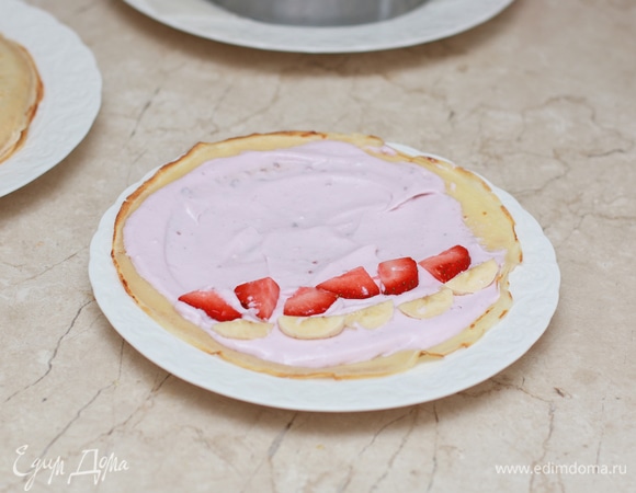 Каждый блинчик смажьте кремом, выложите немного заранее нарезанных фруктов и заверните блинчик в форме рулета.