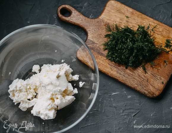 Пока профитроли выпекаются, приготовим начинку: смешайте творожный сыр и небольшой пучок укропа. Зелень можно брать любую по вкусу. Хорошо взбить начинку миксером.
