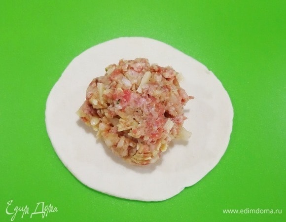 Тесто немного раскатываем и вырезаем небольшие кружки. Рабочую поверхность посыпаем мукой, помещаем на нее кружки теста, выкладываем щедрую порцию начинки.