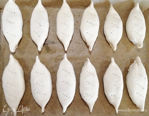 Противень выстелить бумагой для выпечки, смазать оливковым маслом и выложить пирожки швом вниз.