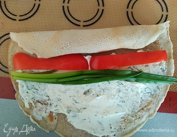 Оставшуюся часть блина намазать сыром. Положить перец и несколько стеблей лука.