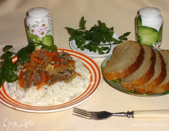 На тарелку выложить порцию риса, сверху положить куриные желудки с овощами, украсить зеленью и подать к столу. Приятного аппетита!