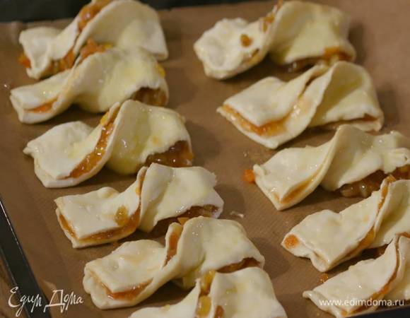 Каждую полоску скрутить посередине, так чтобы получился бантик, выложить на выстеленный бумагой для выпечки противень и смазать сверху яйцом.