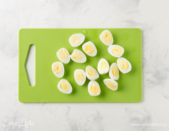 Отварить перепелиные яйца и разрезать пополам.