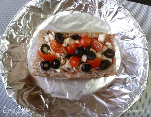 Нарезать шампиньоны небольшими кубиками, помидоры —дольками, маслины — колечками. Заполнить хлебную основу.