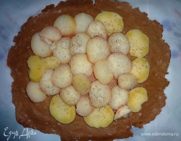 На тесто выложить слой картофеля, не доходя до краев 5–6 см, посолить и поперчить.